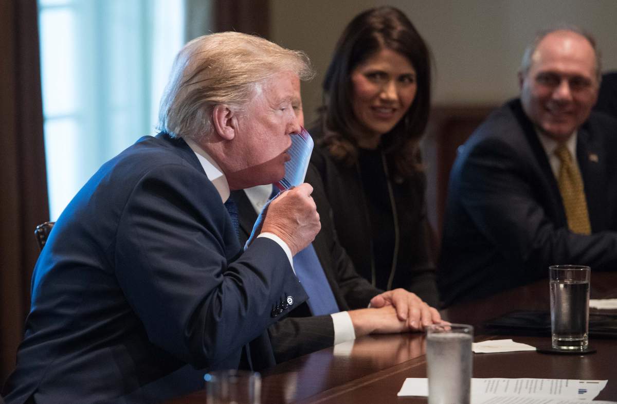 US President Donald Trump kisses a sample of the proposed new tax form as he meets with House Republican leaders and Republican members of the House Ways and Means Committee at the White House in Washington, DC, on November 2, 2017.