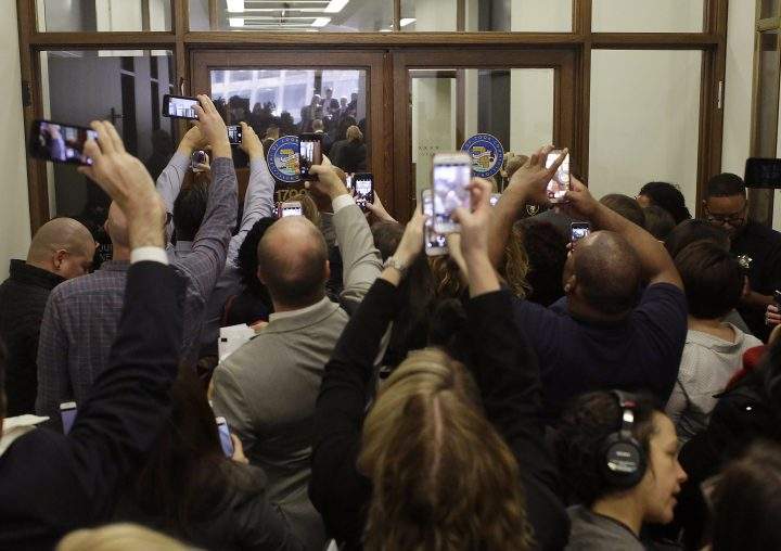 People use their phones to capture former President Barack Obama arriving for Cook County jury duty.