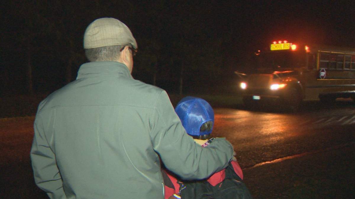 Hanwell mayor Chris Melvin waits outside with his son Spencer for the school bus
