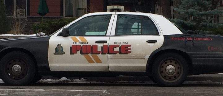 A police car sits near the site of a home invasion where a gun was fired.