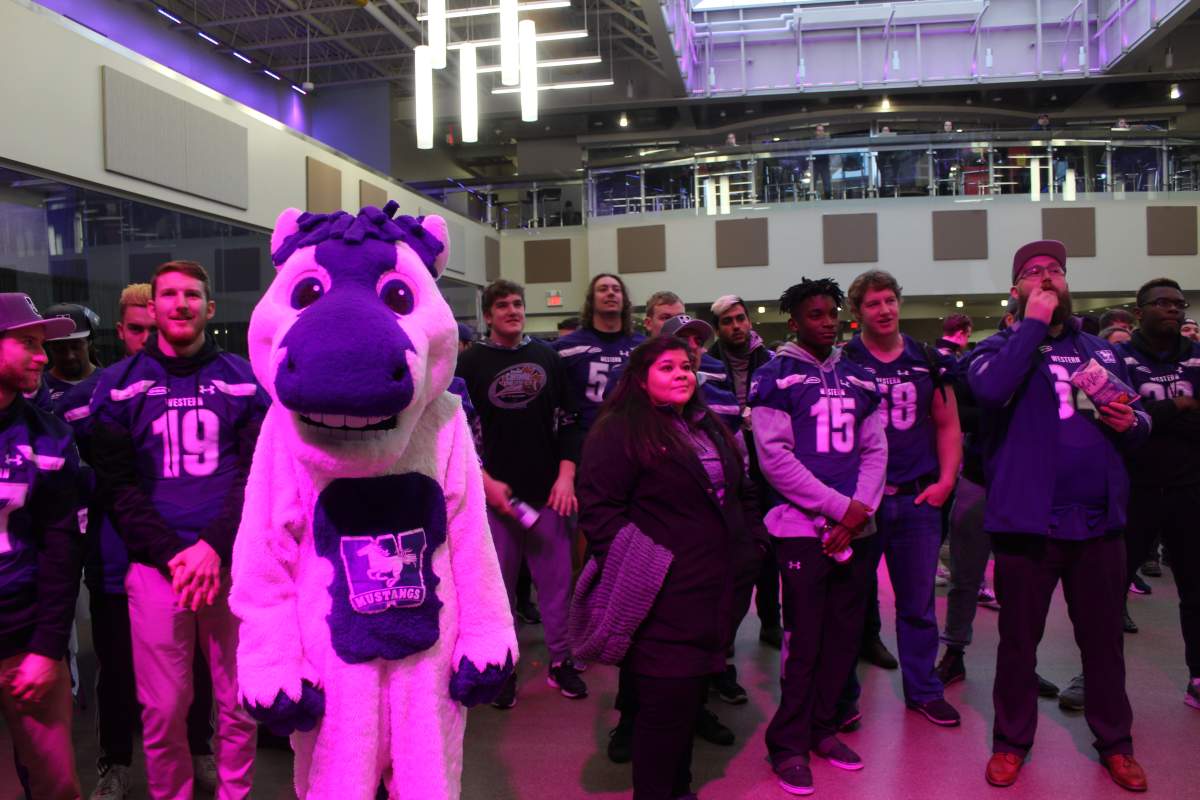 JW, the Western Mustangs mascot, stands with members of the men’s varsity football team during a celebration in the University Community Centre.