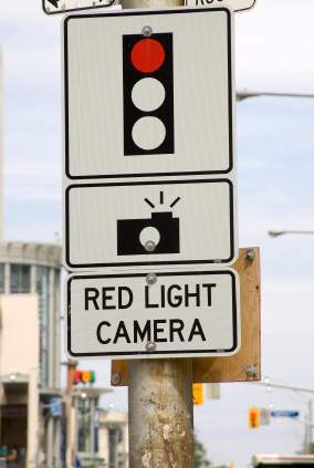 A sign warning of of red light camera ahead of an intersection.