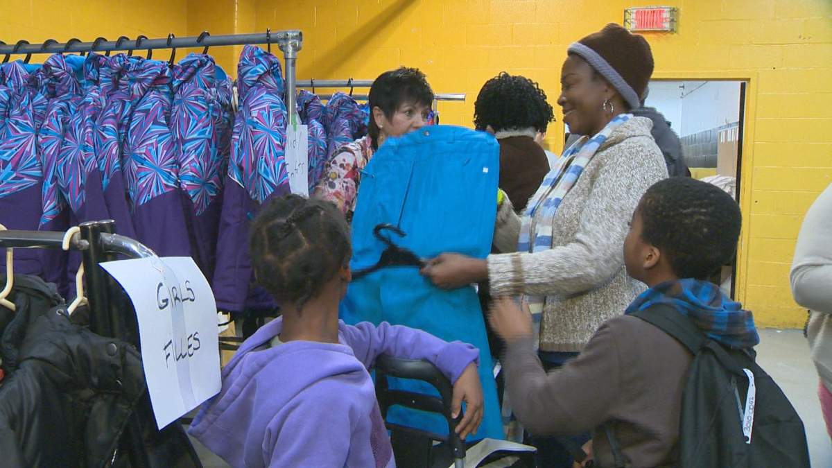 New comer to Canada inspects a pair of snow pants at the Sun Youth winter coat give away. 