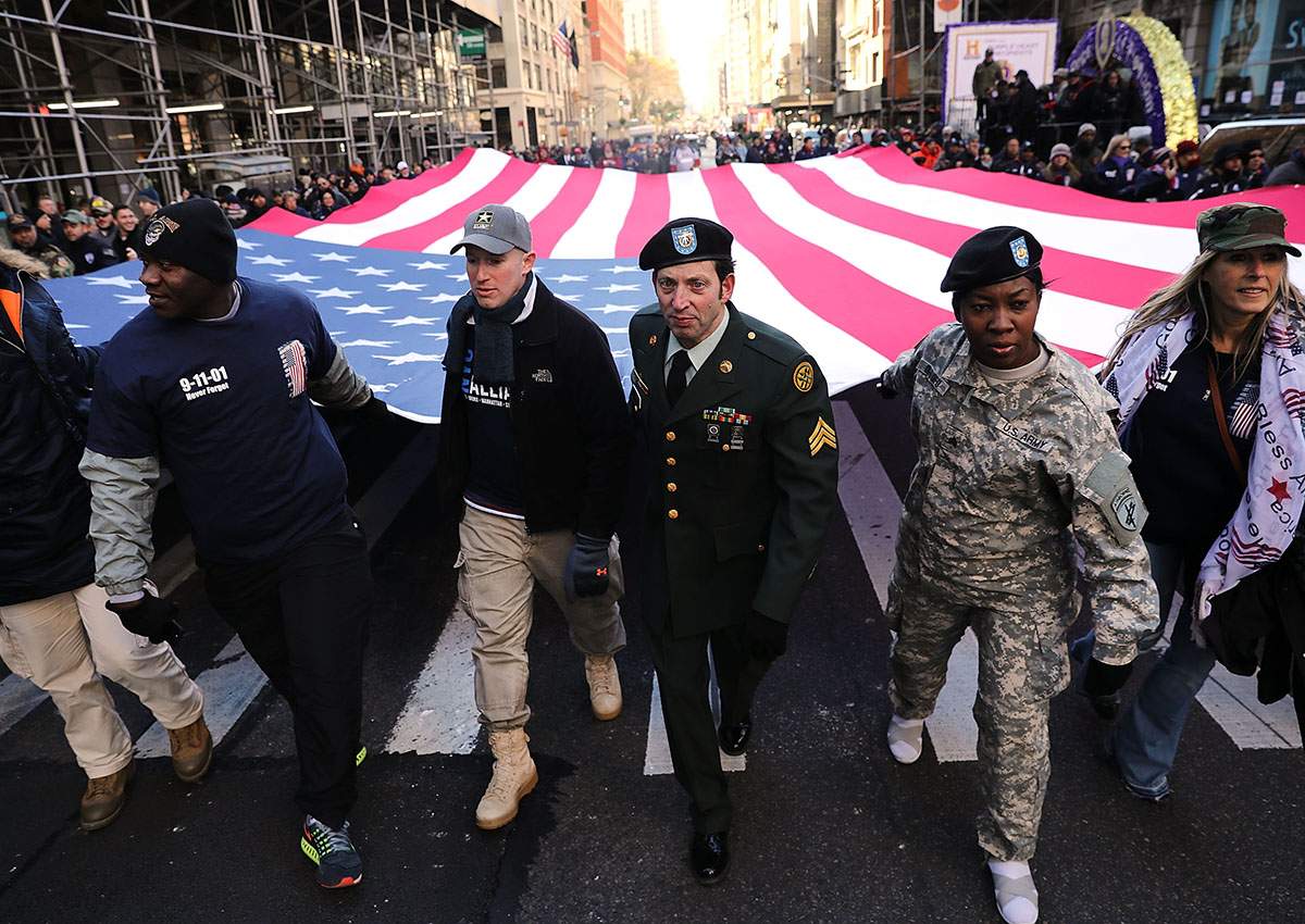 : Soldiers, veterans and civilians carry an American Flag as they march in the Veterans Day Parade on November 11, 2017 in New York City. The largest Veterans Day event in the nation, this year’s parade features thousands of marchers, including military units, civic and youth groups, businesses and high school bands from across the country and veterans of all eras. The U.S. Air Force is this year’s featured service and the grand marshal is space pioneer Buzz Aldrin.