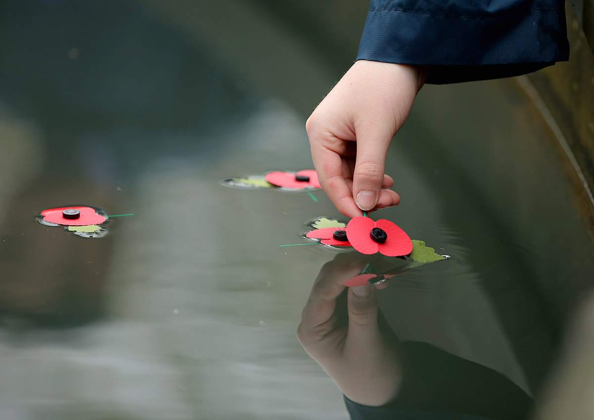 A poppy is placed in the fountain by a young cadet in Swansea, Wales.