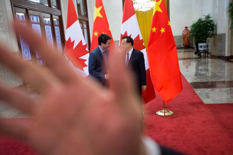 A security guard attempts to block a news photographer as a picture is taken of Prime Minister Justin Trudeau being greeted by Chinese Premier Li Keqiang at the Great Hall of the People in Beijing, on Monday, Dec. 4, 2017.
