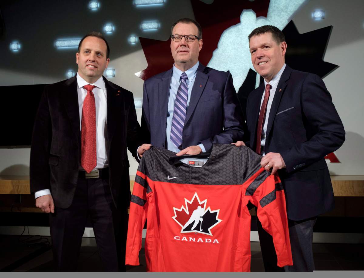 Hockey Canada president and CEO Scott Smith, right, senior manager Shawn Bullock, left, and head scout Brad McEwen, pose with a jersey after announcing the players invited to Canada’s National Junior Team selection camp during a news conference in Calgary, Alta., Wednesday, Dec. 6, 2017.THE CANADIAN PRESS/Jeff McIntosh.