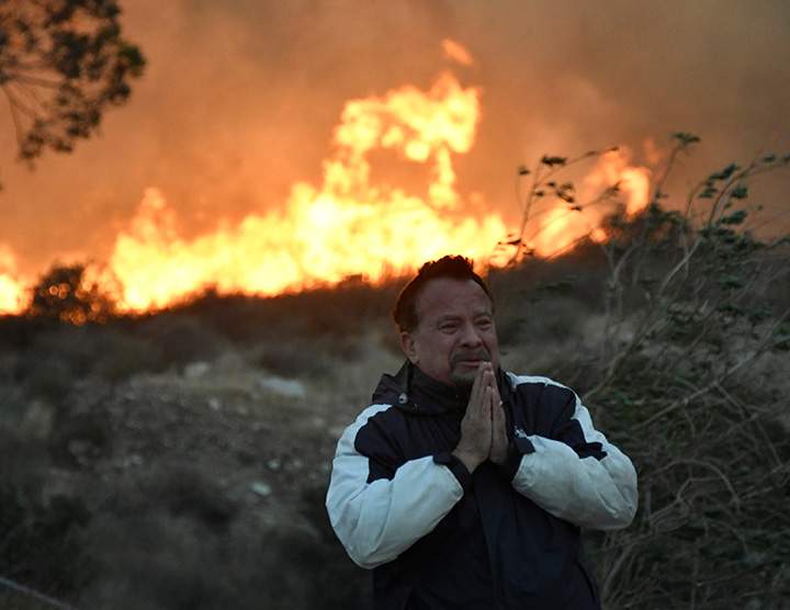 A man prays during an early-morning Creek Fire that broke out in the Kagel Canyon area in the San Fernando Valley north of Los Angeles, December 5, 2017.