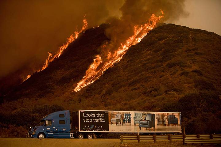 Flames from the Thomas fire burn above a truck on Highway 101 north of Ventura, Calif., on Wednesday, Dec. 6, 2017.