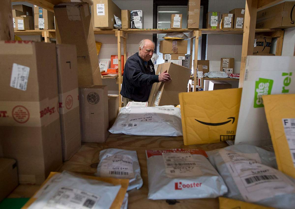 Crow Smith puts a package away in a warehouse among shipping packages waiting to be picked up Monday December 18, 2017 in Ogdensburg, N.Y. 