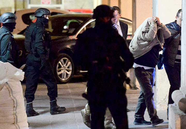 A man covers his face with his jacket as he is escorted to a court in Valletta, Malta, Tuesday, Dec. 5, 2017. 