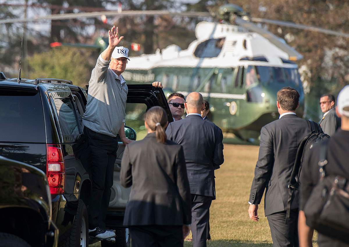 Donald Trump (L) waves as he exits his vehicle after playing a round of golf with Japanese Prime Minister Shinzo Abe.