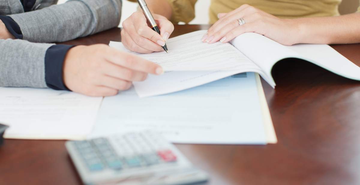 A generic photograph of a person signing paperwork.