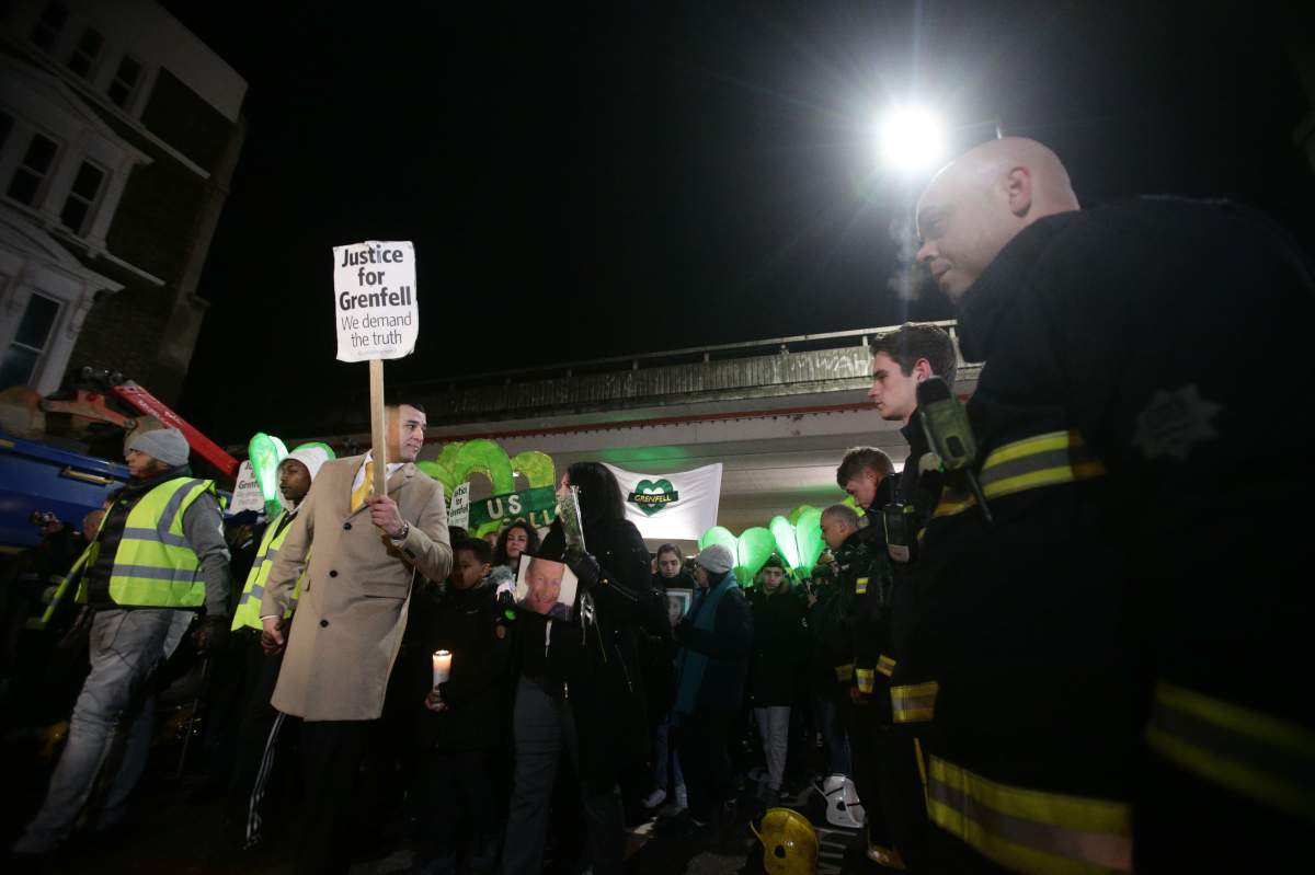 People pass firefighters paying their respects as they take part in a silent walk to mark the six month anniversary of the Grenfell Tower fire, in west London. (Photo by Yui Mok/PA Images via Getty Images)