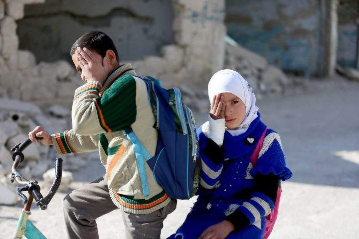 Syrian children holding hand cover his eye in support of Syrian baby Karim.