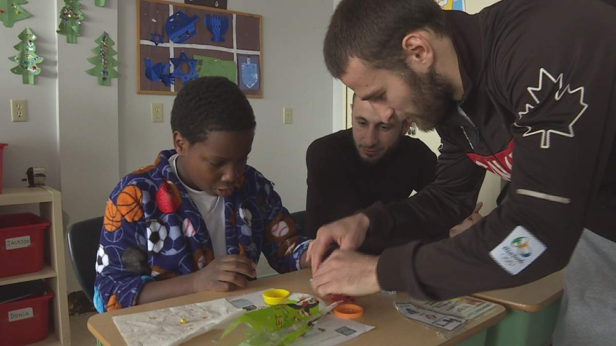 Boxers Arthur Biyarslanov, right, and Vislan Dalkhaev play with a student at the Giant Steps school for kids living with autism, in NDG.  (Global News).