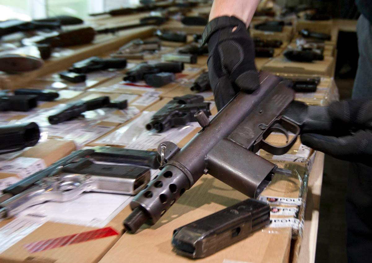 Det. Sgt. Bob Rodeghiero of the Guns and Gangs Task Force shows some of the confiscated weapons during a press conference at 23 Division in Toronto on June 14, 2014.