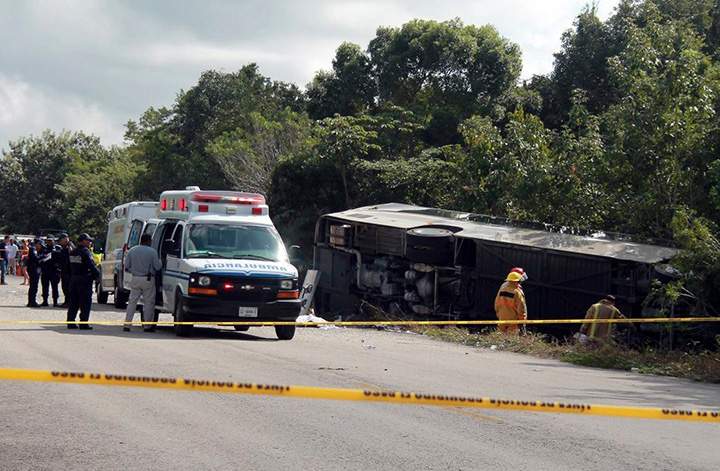 An ambulance sits parked next to an overturned bus in Mahahual, Quintana Roo state, Mexico, Tuesday, Dec. 19, 2017.