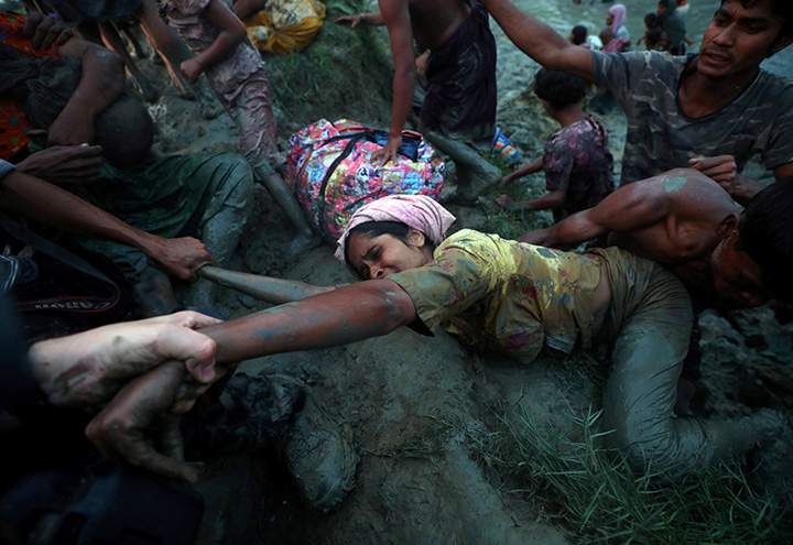 Photographers help a Rohingya refugee to come out of Naf River as they cross the Myanmar-Bangladesh border in Palong Khali, Bangladesh, November 1, 2017.
