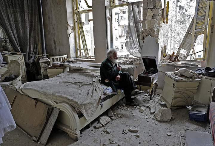 A man smokes his pipe as he sits in his destroyed bedroom listening to music on his vinyl player in Aleppo’s formerly rebel-held al-Shaar neighbourhood.