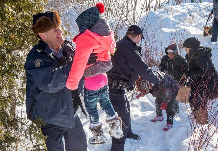 Family members from Somalia are helped across the border into Canada from the United States Friday, February 17, 2017 near Hemmingford, Que.