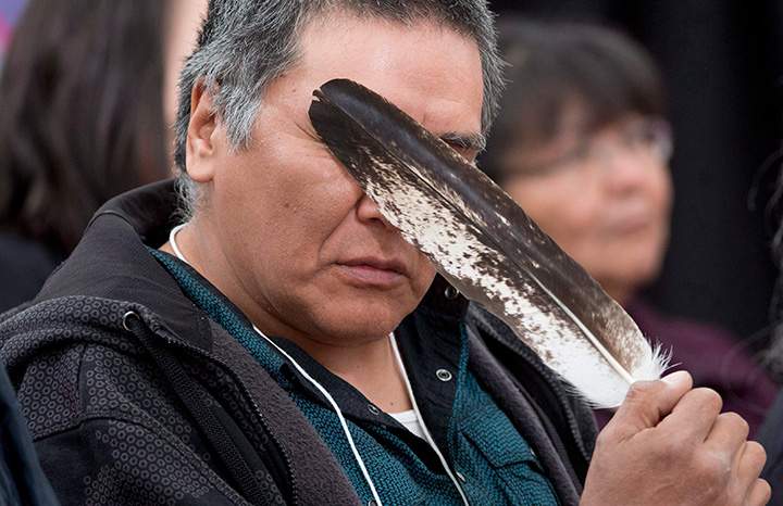 Terry Ladue holds an eagle feather to his face after speaking of his mother’s murder at the National Inquiry into Missing and Murdered Indigenous Women and Girls in Whitehorse, YT., June 1, 2017.