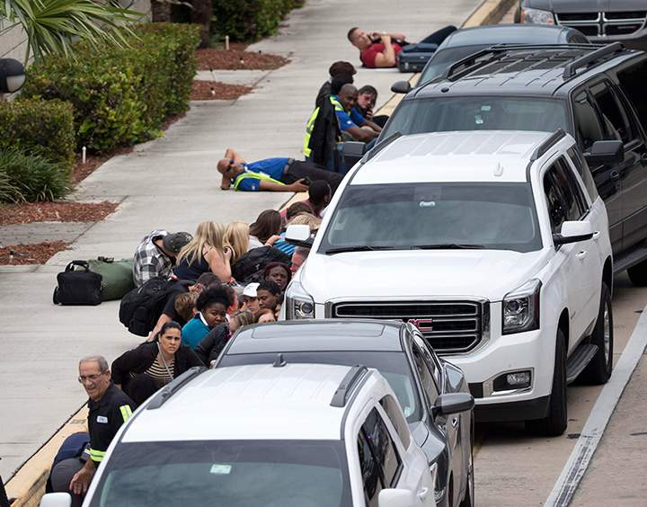 People take cover outside Hollywood International Airport in Fort Lauderdale, Fla., on Jan. 6, 2017, after a shooter opened fire inside a terminal at the airport.