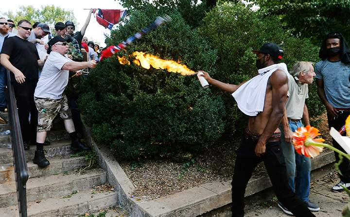 A counter-protester uses a lighted spray can against a white nationalist at the entrance to Lee Park in Charlottesville, Va., on Aug. 12, 2017.