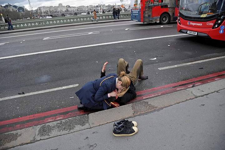 A woman assists an injured person after a terror attack on Westminster Bridge in London, Britain, March 22, 2017.