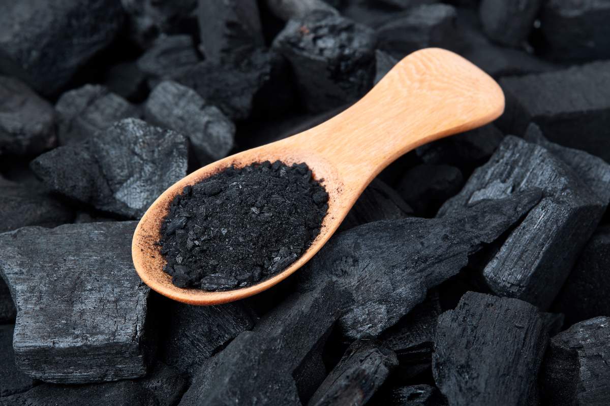 Black particles charcoal on a wooden spoon.
