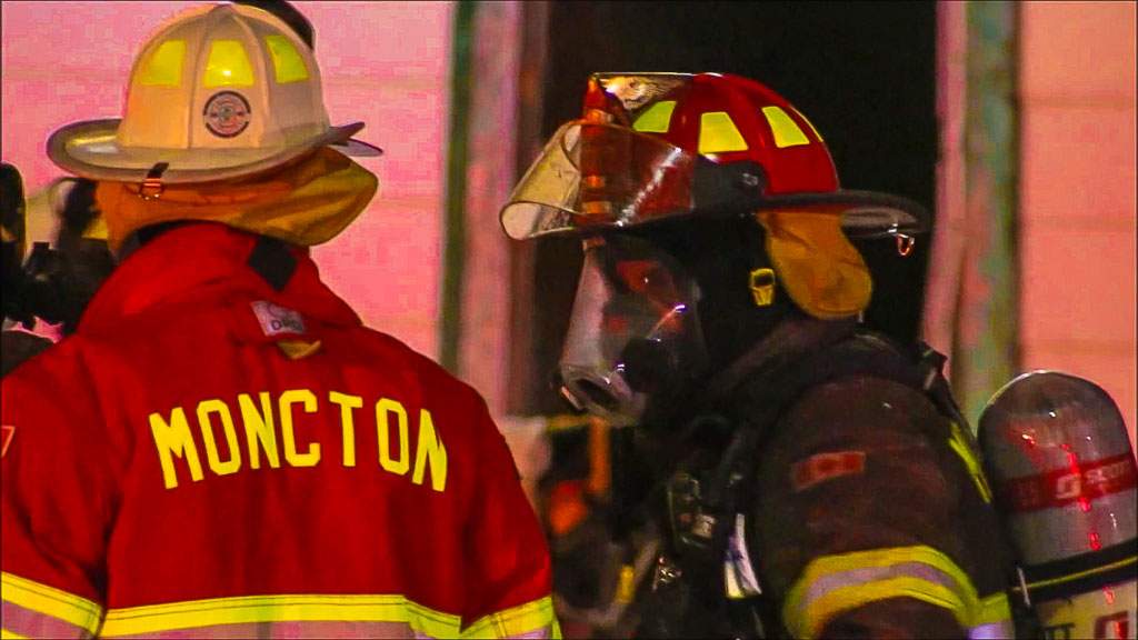 File - Members of the Moncton Fire Department stand outside a fire on the morning of Dec. 15, 2017.