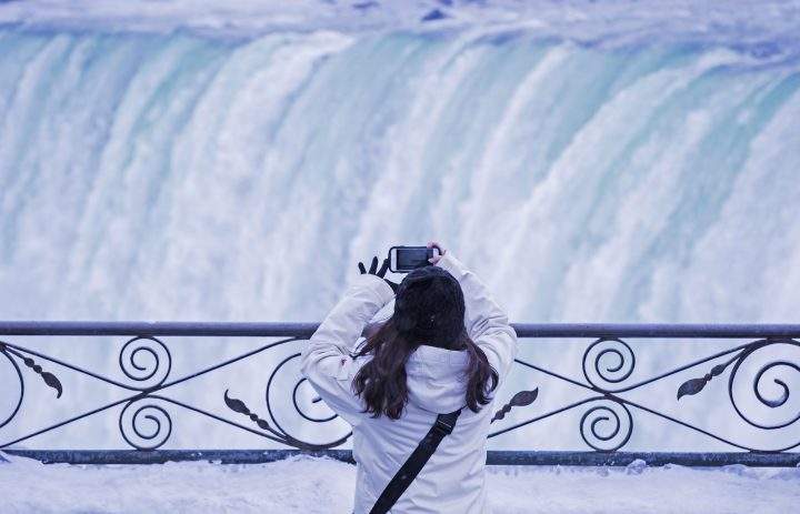 A visitor takes a photograph at the brink of the Horseshoe Falls in Niagara Falls, Ont. on Dec. 29, 2017.