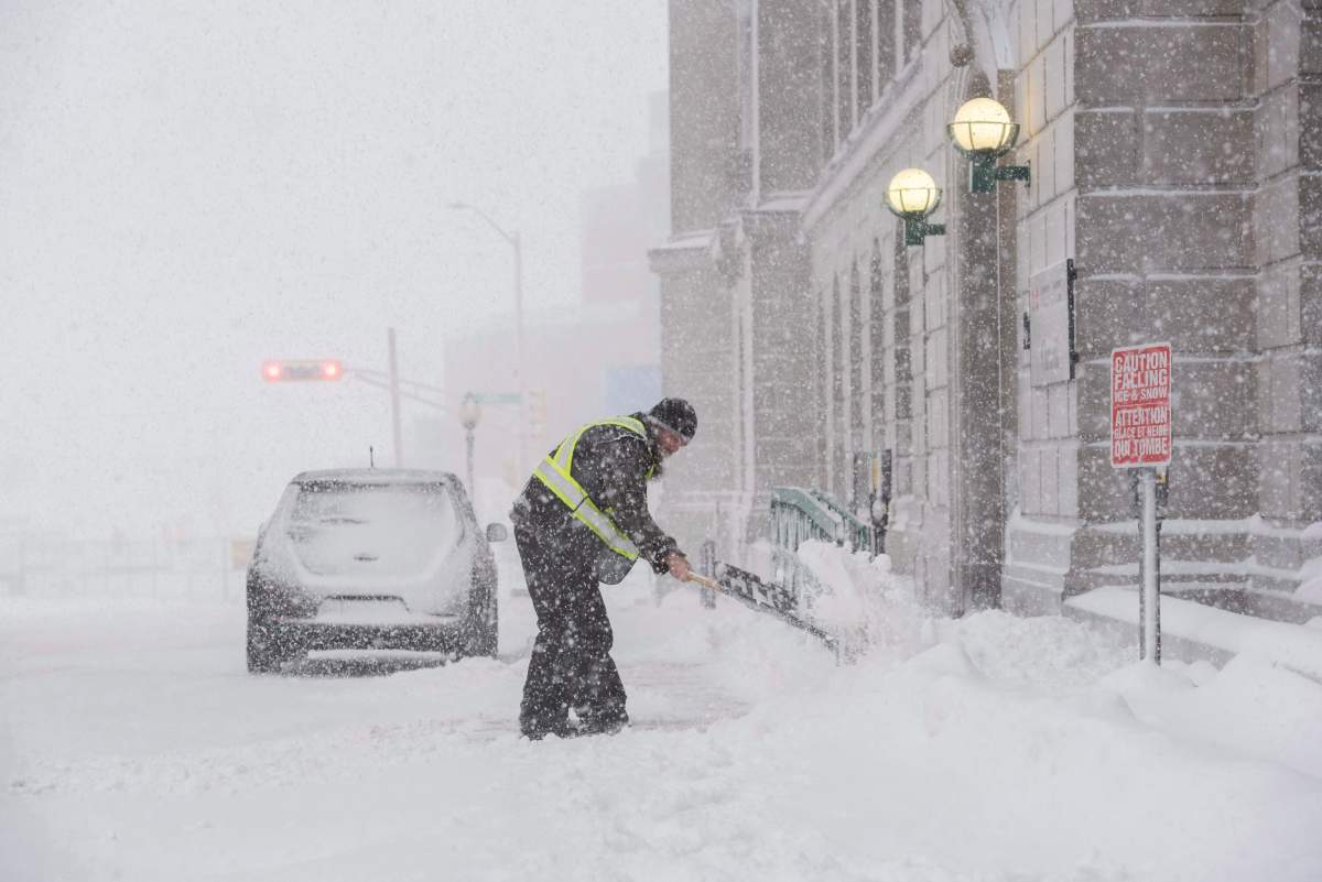 Josh Douthwright shovels snow at the entrance to the Federal Building on Highfield Street in downtown Moncton, N.B., on Thursday, January 4, 2018.