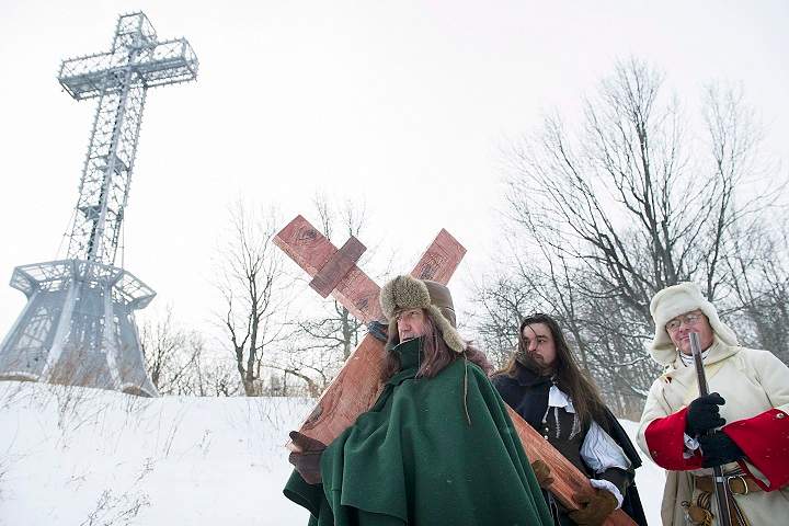 A man dressed as Paul de Chomedey de Maisonneuve, left, carries a crucifix to commemorate the 375th anniversary of the raising of the cross on Mount Royal in Montreal, Saturday, January 6, 2018.