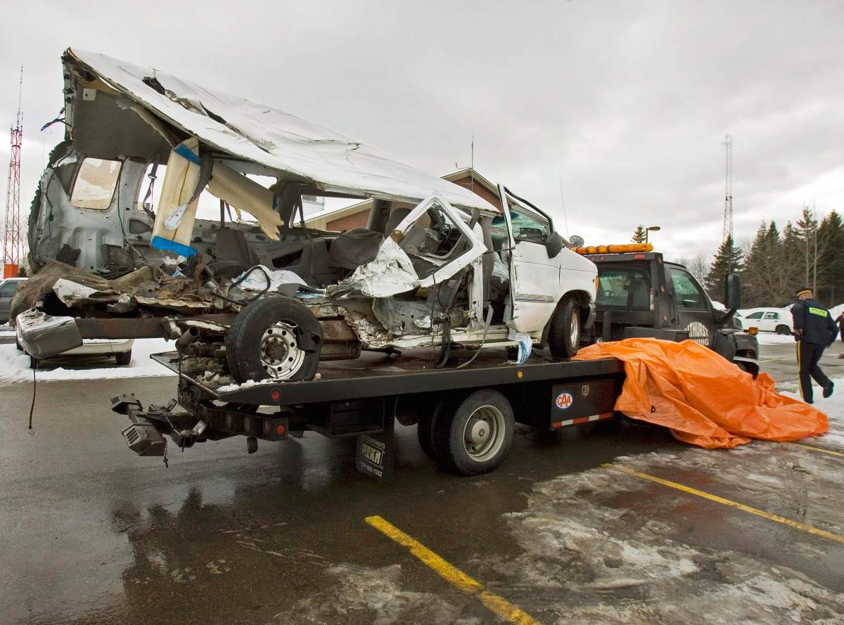 An RCMP officer walks past a van that was carrying the Bathurst High School boys’ basketball team that collided with a transport truck while returning from a game in Bathurst, N.B., on Saturday, Jan. 12, 2008.
