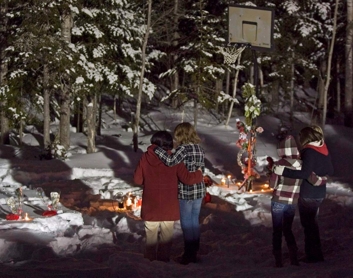 Family and friends pay their respects as they hold a vigil at the crash scene to mark the anniversary of the tragic accident that took the lives of seven high school basketball players and a teacher one year ago, in Bathurst, N.B. early on Monday, Jan. 12, 2009.  