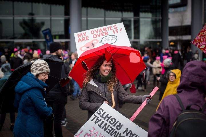 A woman holds an umbrella with a sign and hearts attached to it during a women’s march in Vancouver, B.C., on Saturday January 20, 2018.