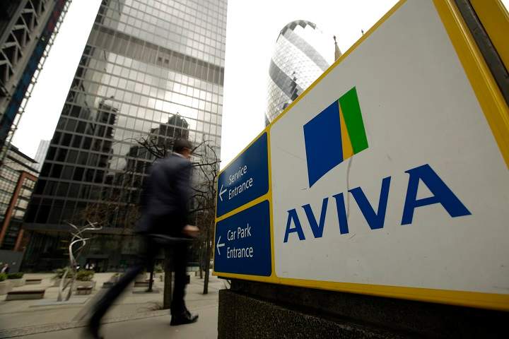 A pedestrian passes a sign outside the headquarters of Aviva Plc in London, U.K., on Friday, March 7, 2014.