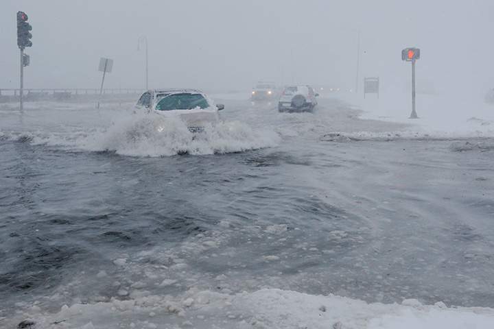 Drivers make their way along a flooded road in the Boston suburb of Lynn, Massachusetts, Jan. 4, 2018.