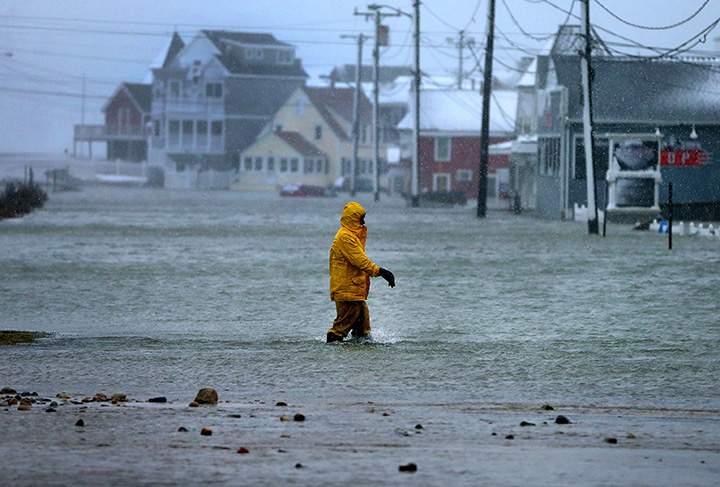 A man walks through a flooded section of Brant Rock in Marshfield, Mass., on Jan. 4, 2018.