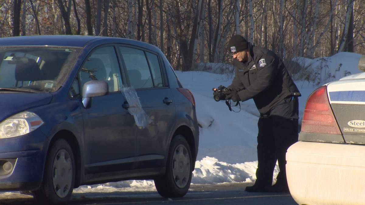 A police officer photographs a car outside a north end Dartmouth building where police say a suspicious death occurred on Sunday.