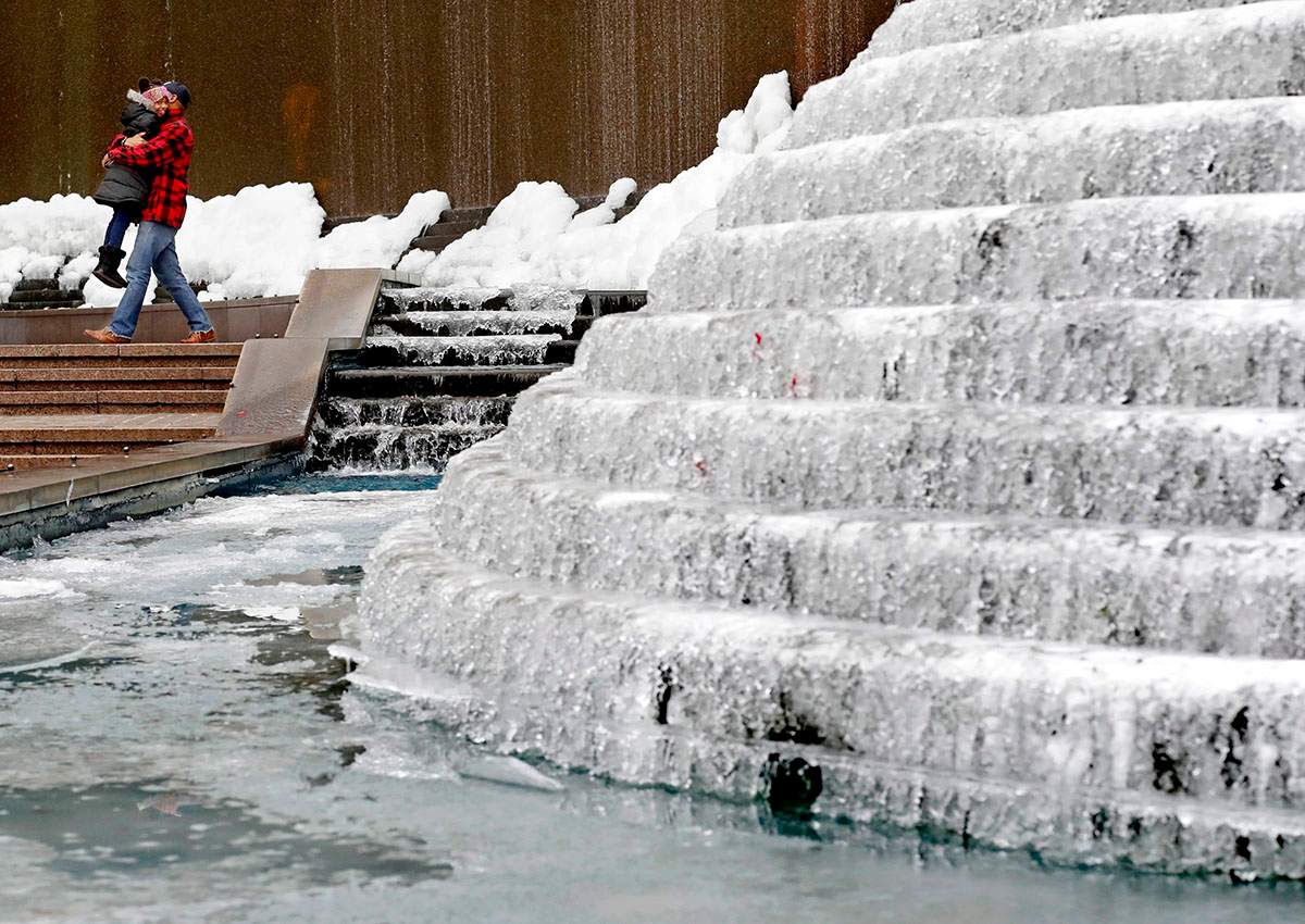 Kenneth Freeman, carries his daughter Alora, 8, as they visit a frozen water fountain downtown in Atlanta, Wednesday, Jan. 3, 2018.