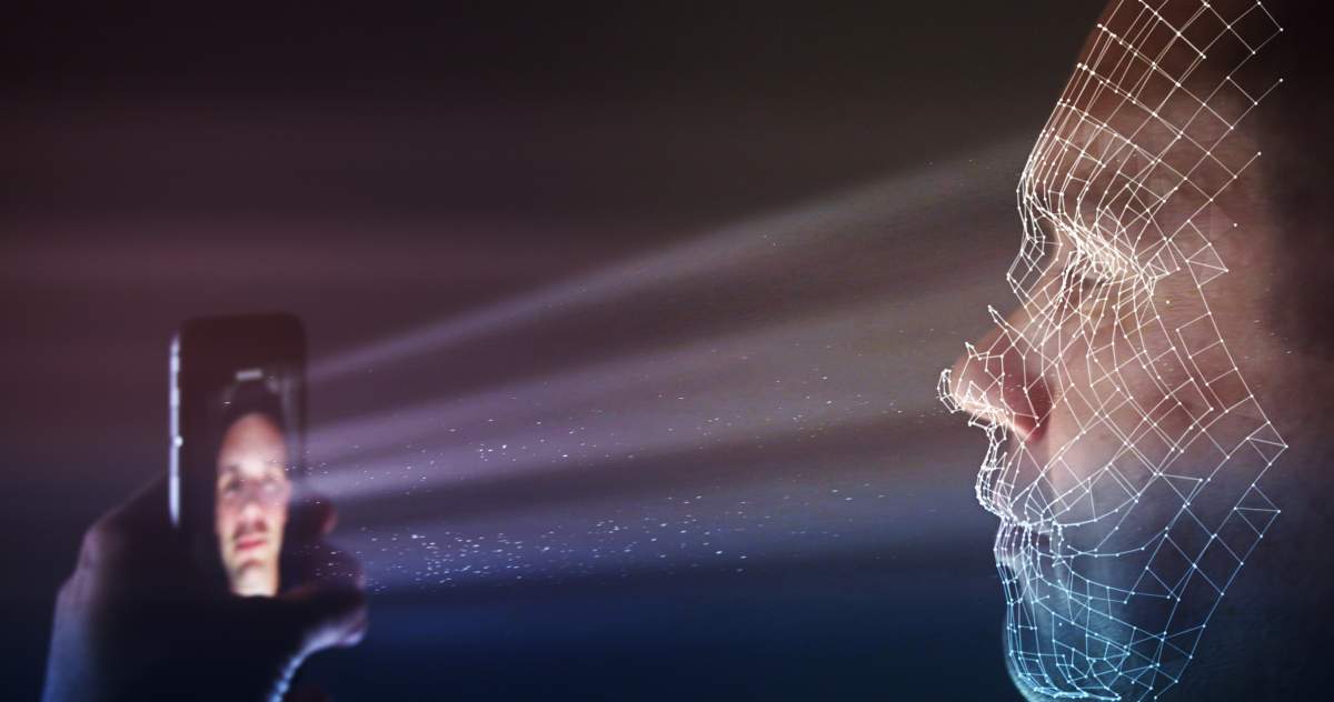 A man uses the latest smartphone technology for a biometric facial recognition unlock. Filmed with a dark background, facial wire mesh and points tracking the viewer’s face unlock the phone.