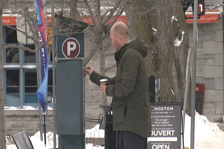 A man feeds an on-street parking meter on Ontario Street in Kingston, Ontario.