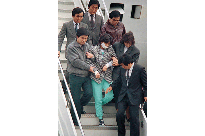 In this Dec. 15, 1987 file photo, North Korean spy Kim Hyon-hui, centre, is taken out from a plane upon her arrival in Seoul, South Korea, from Bahrain, after she bombed a Korean Air jetliner.