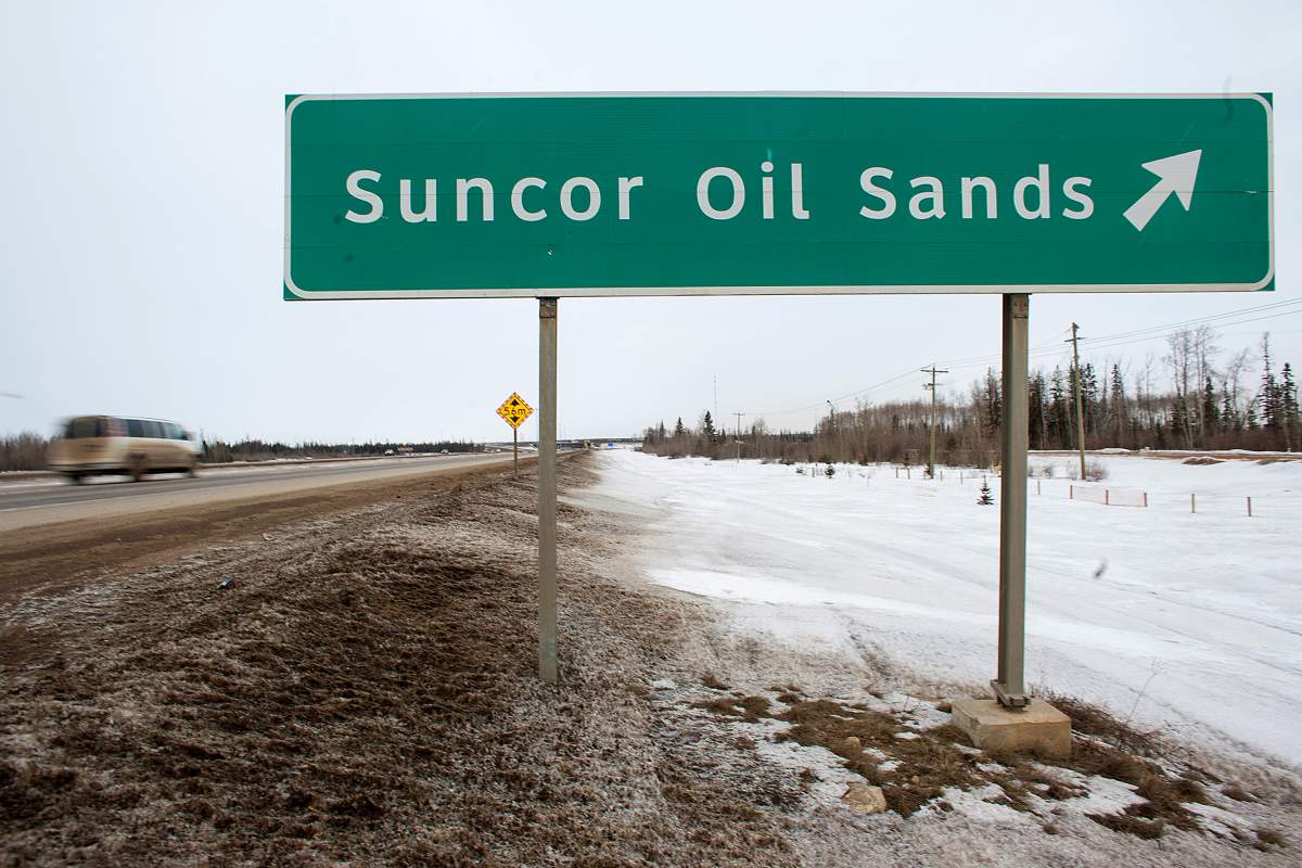 FILE: A sign directing traffic to the Suncor Energy Inc. base plant stands at the Athabasca Oil Sands near Fort McMurray, Alberta, Canada, on Tuesday, March 26, 2013. 