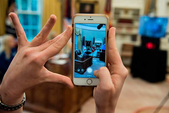 A woman uses an iPhone to take a SnapChat as U.S. President Donald Trump speaks in the Oval Office of the White House April 24, 2017 in Washington, DC. 