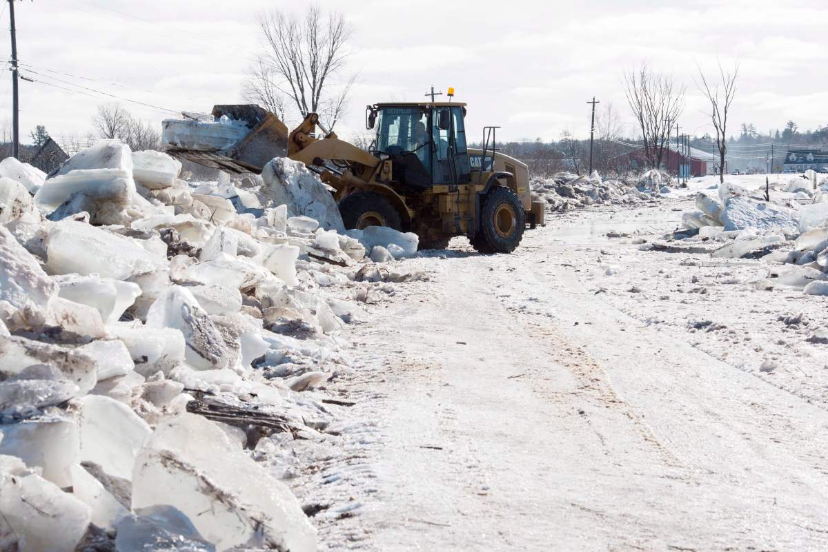 Tim McCann uses a front end loader to remove ice off of Route 101 in Hoyt, N.B., on Sunday, Jan. 14, 2018. 