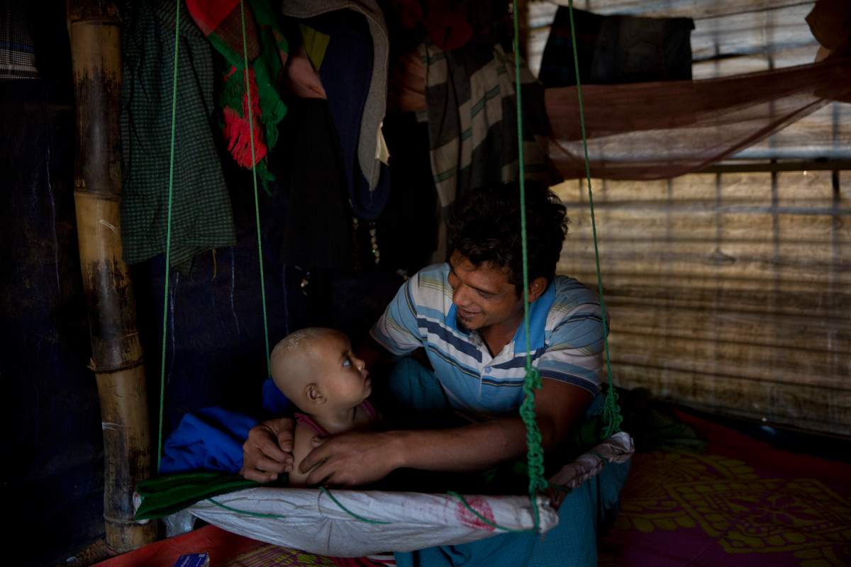 In this Jan. 21, 2018 photo, Rohingya Muslim refugee Noor Kadir, 24, from the Myanmar village of Gu Dar Pyin, plays with his son inside the family makeshift shelter in Balukhali refugee camp.