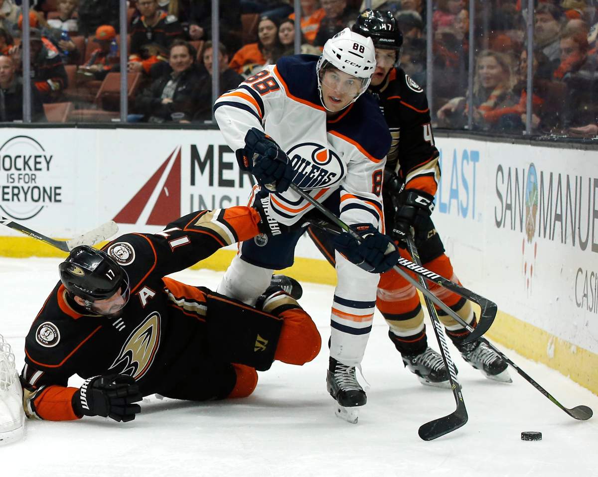 Edmonton Oilers defenseman Brandon Davidson, center, steps over Anaheim Ducks center Ryan Kesler, left, to control the puck as defenseman Hampus Lindholm, of Sweden, trails during the second period of an NHL hockey game in Anaheim, Calif., Friday, Feb. 9, 2018. (AP Photo/Alex Gallardo).